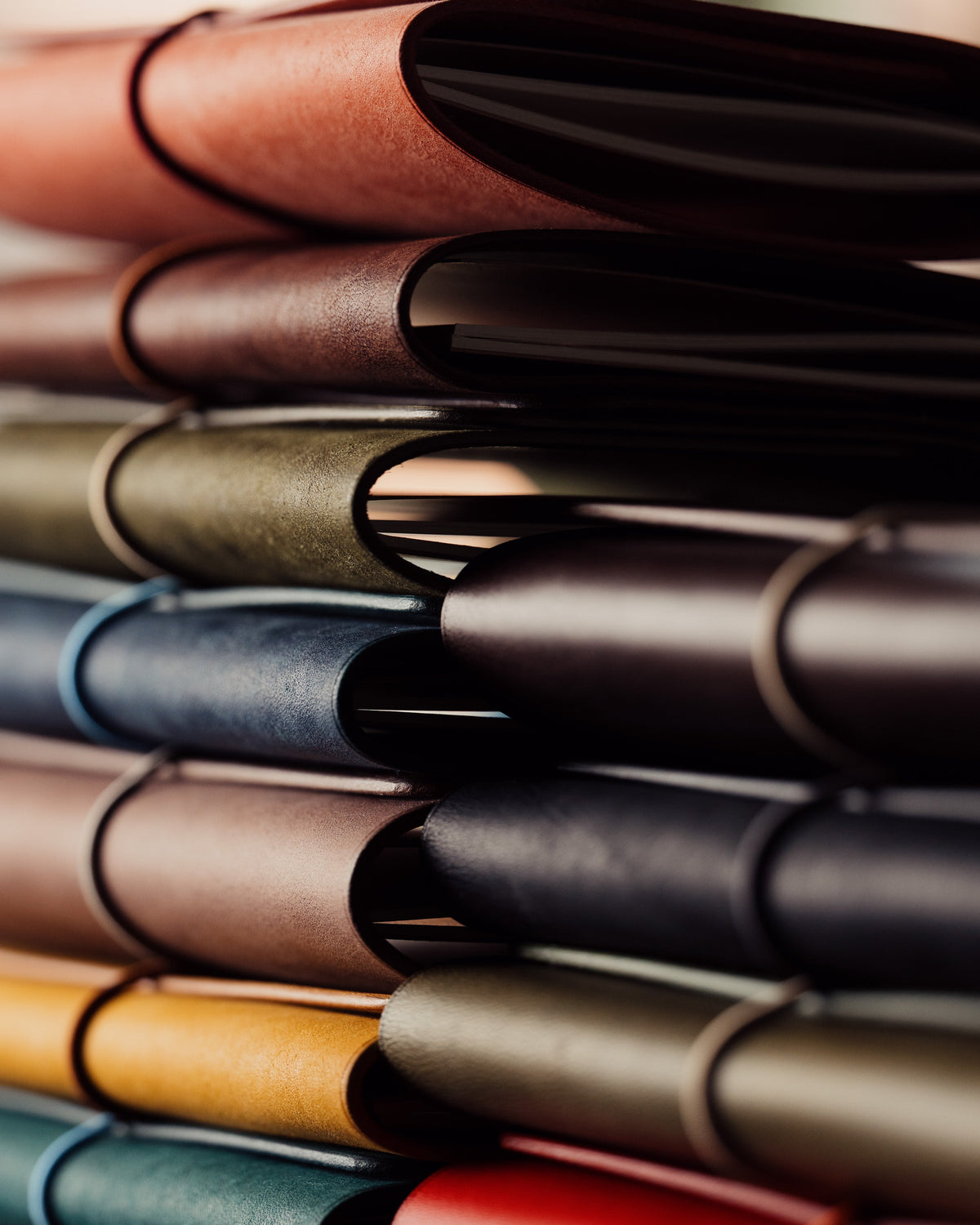 Leather-covered notebooks stacked at different angles, with curved spines and paper edges catching the light.