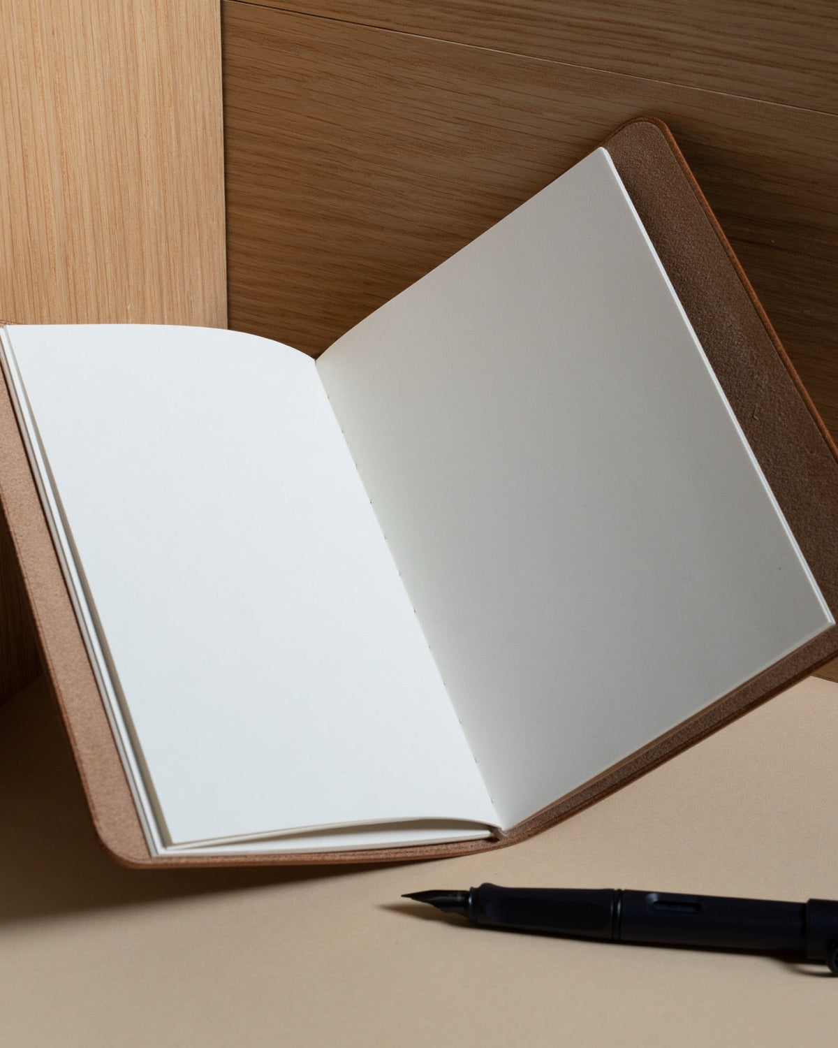 An open notebook in a leather cover showing two blank pages