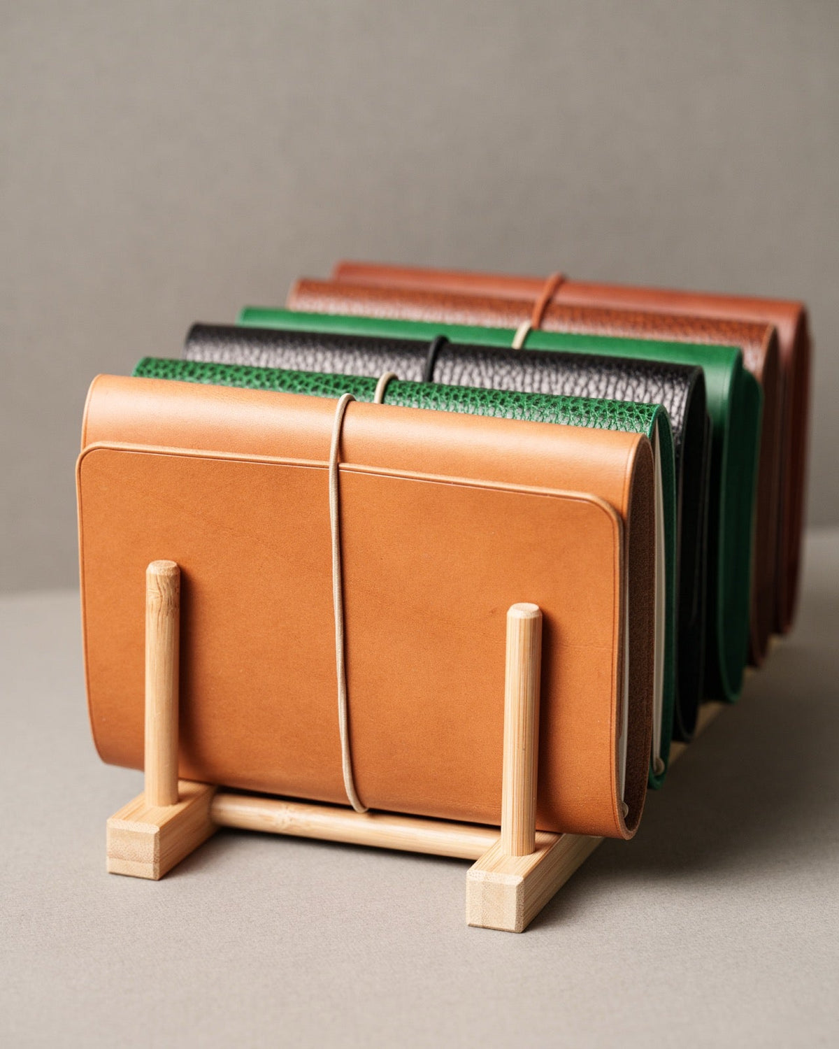 Leather notebook covers of different colours and grains standing in a wooden rack