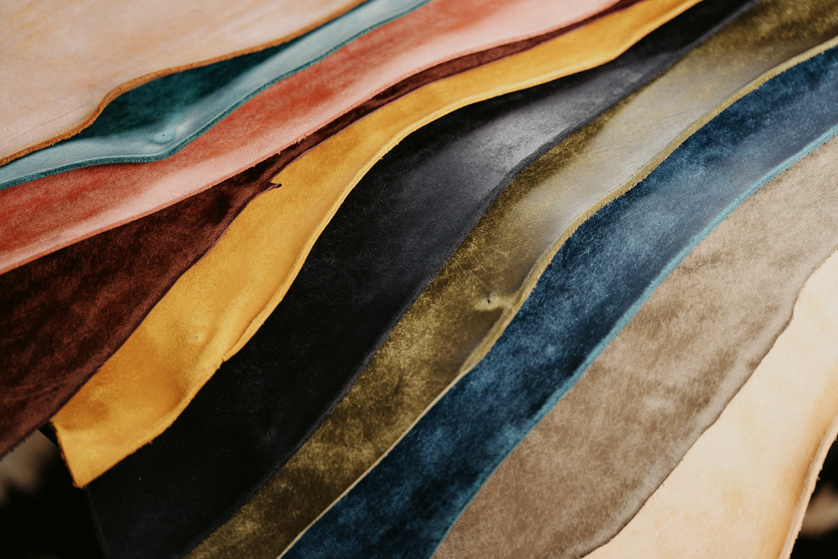 Overlapping sheets of leather in blue, green, yellow, pink and brown, with their natural edges visible.