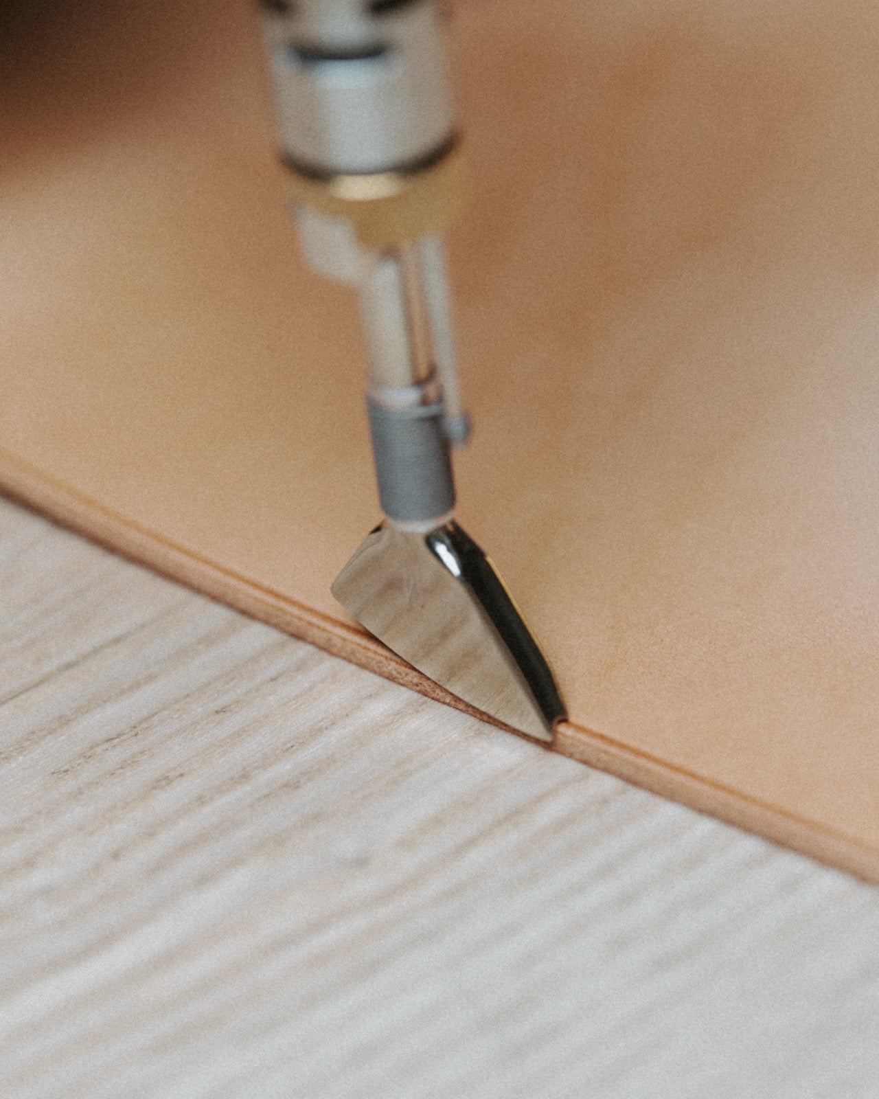 Edge-finishing tool shaping the edge of a natural tan leather cover